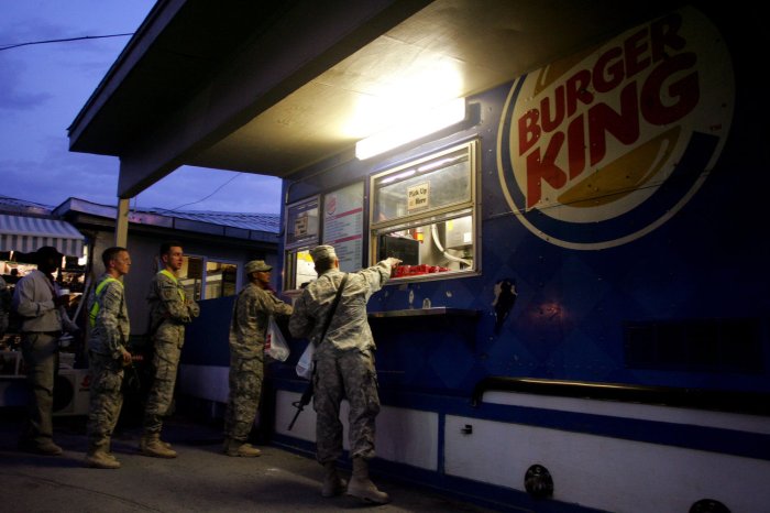 U.S. service members stand in line to get their hamburger at Burger King at...