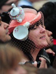 A woman with a tea pot inspired hat watches outside Westminster Abbey in London