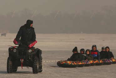 Chinese tourists go for a ride on the frozen Songhua River in Harbin