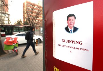 Chinese walk past a news stand selling President Xi's manifesto in Beijing, China