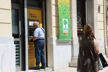 Greek citizens use an ATM machine in Athens