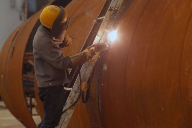 A Chinese welder works on huge steel pipes in Chongqing