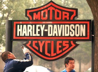 Chinese workers erect a Harley-Davidson sign in China