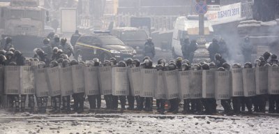 Ukrainian riot police stand near a barricade