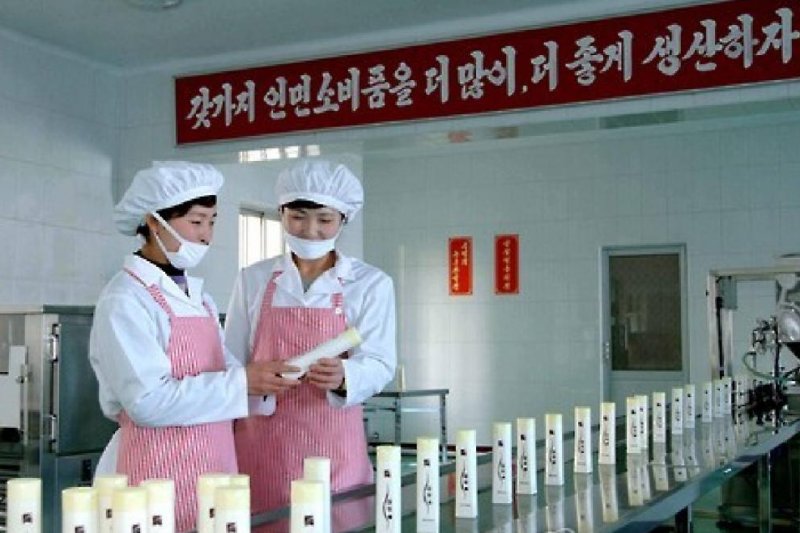 Workers at Pyongyang Cosmetics Factory. The sign above translates, "Let's make more and better products for the people." Photo by Yonhap