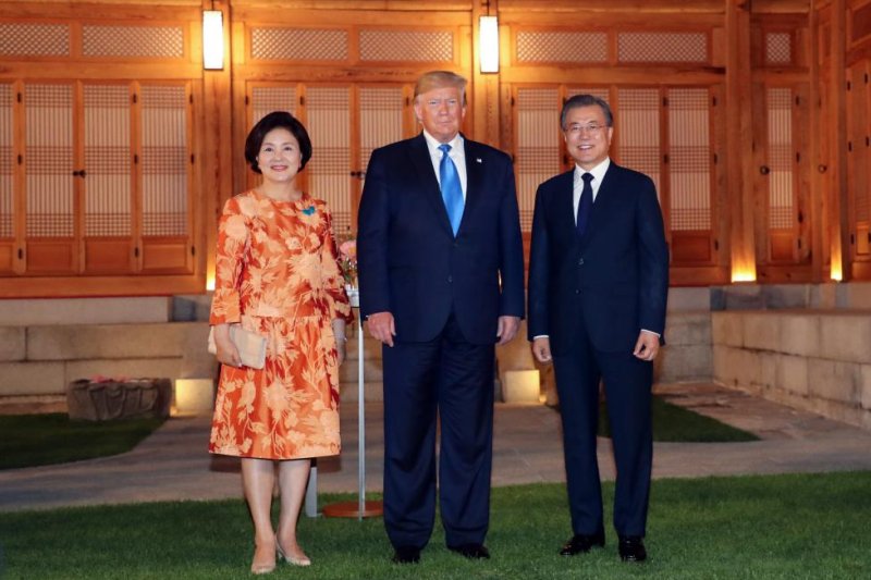South Korean President Moon Jae-in (R) and his wife, Kim Jung-sook (L), pose for a photo with U.S. President Donald Trump (C) before a welcome dinner at the presidential Blue House in Seoul on Saturday. Kim’s choice of jewelry, a turquoise butterfly pin, is being criticized by South Korea’s political opposition. File Photo by Yonhap/EPA-EFE