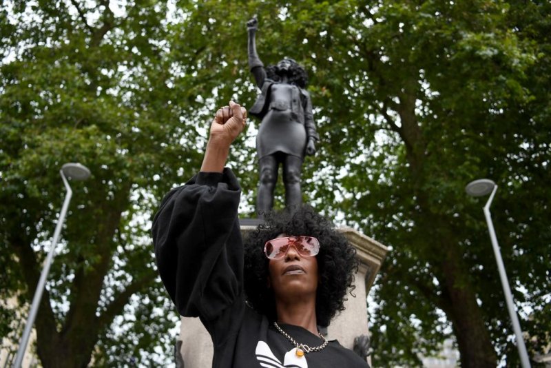 Activist Jen Reid poses with a raised fist in front of a new statue that appeared in Bristol, Britain, on Wednesday. A sculpture of former British lawmaker and known slave trader&nbsp;Edward Colston previously stood at the location. Photo by Neil Hall/EPA-EFE