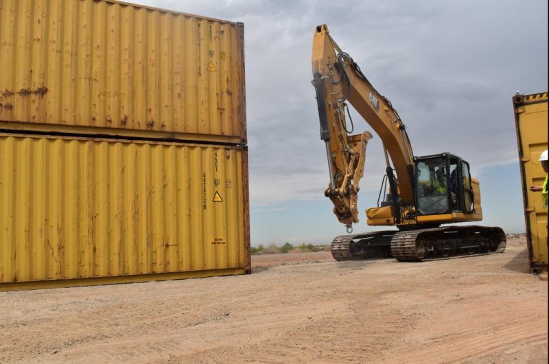 Workers stack shipping containers to serve as a makeshift wall along the U.S.-Mexico border in an area of Arizona where there's a gap between the permanent wall. Photo courtesy Arizona Gov. Doug Ducey/Twitter