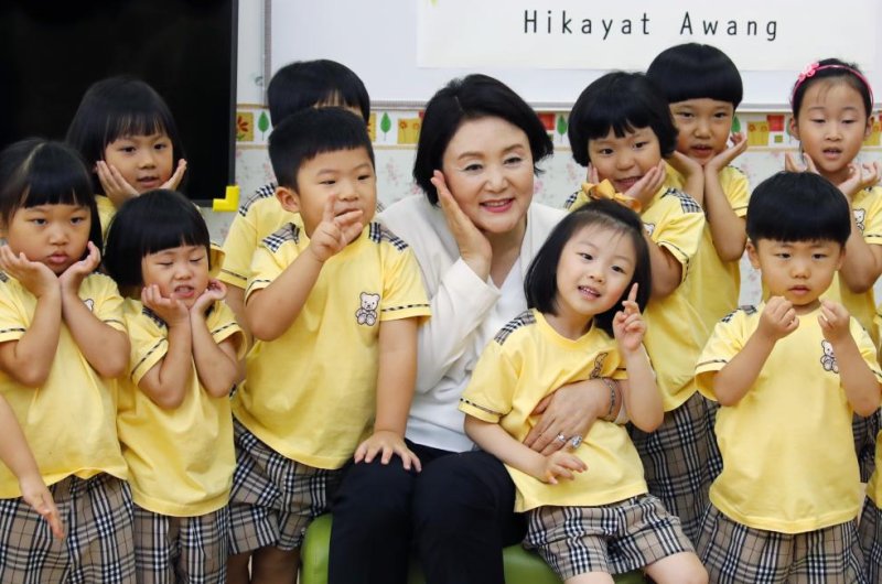 South Korean first lady Kim Jung-sook (C) poses for a photo with a group of South Korean children at a South Korean school in the town of Cyberjaya, Malaysia, on Wednesday. The first lady visited a Malaysian science high school on Thursday. File Photo by Yonhap/EPA-EFE