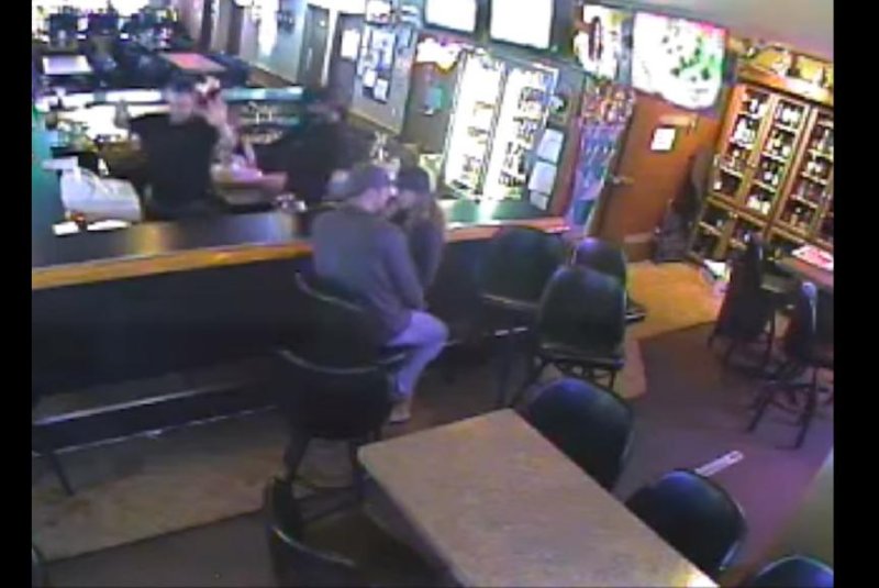A kissing couple fail to notice an armed robbery taking place mere feet away. Screenshot: Billings Gazette/YouTube