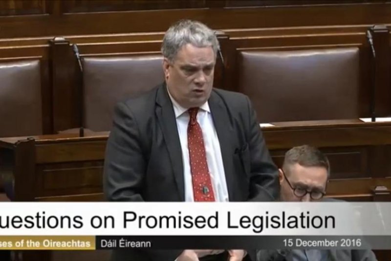 Irish lawmaker Aengus O Snodaigh is interrupted by his own musical Christmas tie while addressing the legislature. Screenshot: Storyful