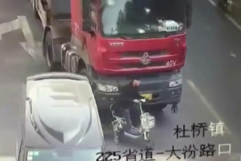 A man riding a scooter is about to be run over by a truck. Screenshot: Newsflare