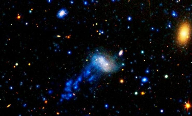 Ultraviolet image of dwarf galaxy IC 3418 in the Virgo cluster shows a gas trail streaming behind it, which a new study presents as evidence the galaxy is dying. (NASA/JPL-Caltech)