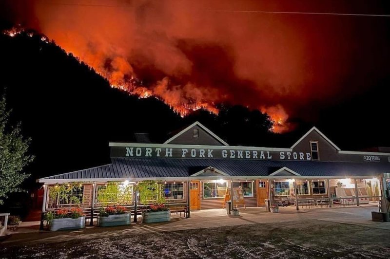 The Moose Fire is seen burning behind North Fork Store in Idaho on Monday. Photo by Dan Peters/<a href="https://inciweb.nwcg.gov/incident/photograph/8249/10/132711">National Wildfire Coordinating Group</a>