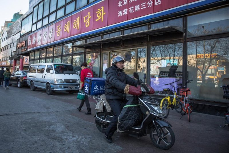 A Chinese food deliverer rides on a scooter next to a North Korean restaurant in Beijing, China, Dec. 22, 2017. By early January 2018 all North Korean companies, including Chinese-North Korean joint ventures, operating in China had to be shut down as part of Beijing's efforts in implementing U.N. sanctions. Photo by Roman Pilipey/EPA-EFE