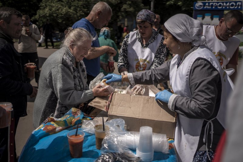 A woman eats food given to her by volunteers at a food delivery station run by a Hare Krishna group in Kharkiv, Ukraine, on May 20. Many Ukrainians have been moved to Russia. File Photo by Ken Cedeno/UPI