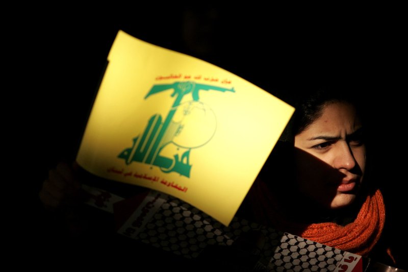 An Iranian woman holds a poster with Hezbollah's signas. (UPI Photo/Mohammad Kheirkhah)