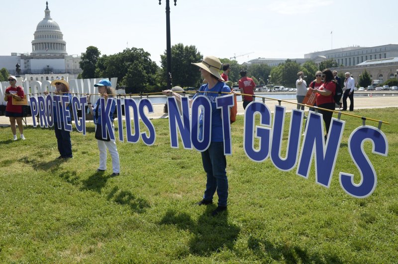 Protesters hold a sign that says "Protect Kids Not Guns" during a rally outside the U.S. Capitol in Washington in June. File Photo by Bonnie Cash/UPI