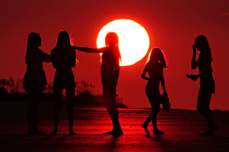 Young women are silhouetted against a dramatic sunrise appearing as a giant ball over the beach in Isle of Palms, South Carolina on July 9, 2023. Scientists note that global temperatures were the hottest in the modern history of Earth due mainly to climate change brought on the continued burning of fossil fuels and the El Nino weather patterns. File Photo by Richard Ellis/UPI