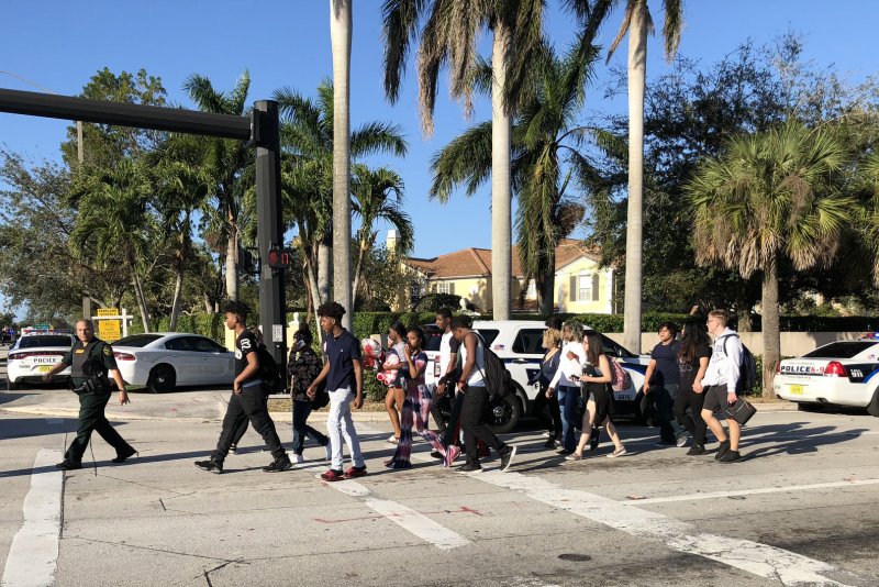 Parents are escorted to a holding area Wednesday to wait for their children near Marjory Stoneman Douglas High School in Parkland, Fla., where a shooting killed 17 people and injured several more. Photo by Gary Rothstein/UPI