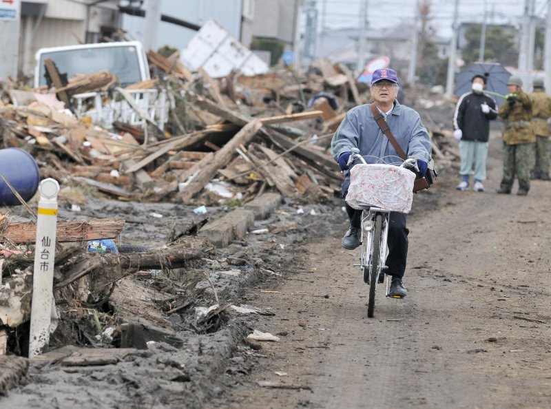 A man rides his bicycle as destruction is seen in Sendai, Miyagi prefecture, Japan, on March 15, 2011. More than 10,000 people are believed to have been killed by a massive earthquake and resulting tsunami. UPI/Keizo Mori | <a href="/News_Photos/lp/d960293b16111aeb7331777d80f3b83d/" target="_blank">License Photo</a>