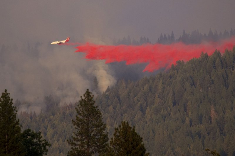 A firefighting plane drops retardant along the fire line over Grizzly Flats, Calif., on Tuesday as the Caldor Fire burns below. Photo by Peter DaSilva/UPI
