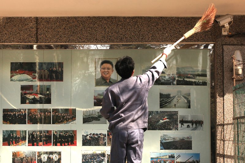 A Chinese maintenance worker cleans the North Korean embassy's display case in Beijing. Kim idolization is required of Chinese residents in North Korea, where as foreigners they are still required to donate money to the regime. File Photo by Stephen Shaver/UPI