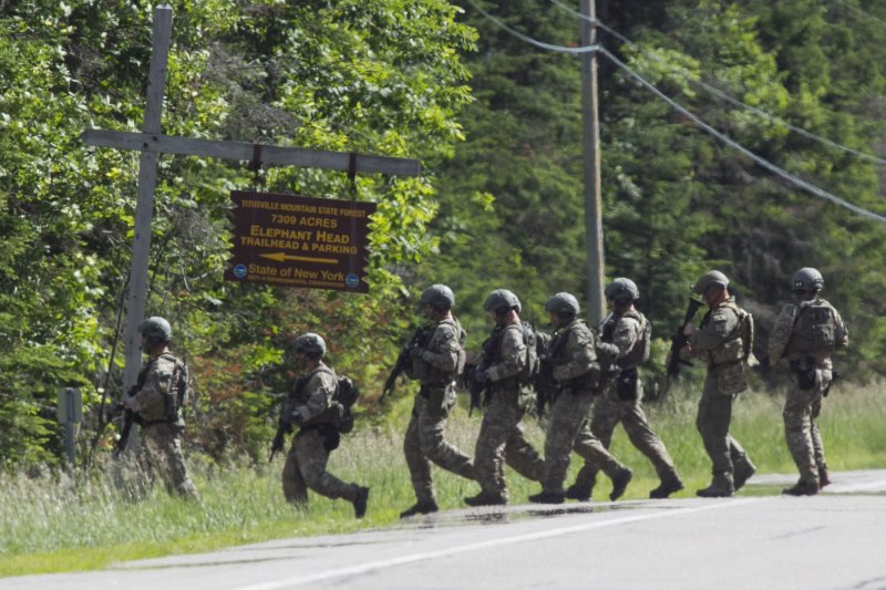 A tactical team marches into the woods along Route 30 at the Elephant Head trail in Malone, New York where escaped prisoner Richard Matt is believed was shot dead on Friday. Law enforcement were called to Route 30 by a 911 call from a motorist who heard shots fired. A second prisoner David Sweat is still on the loose, but police said Sunday they found his DNA near the area Matt was killed. Photo by Matthew Healey/UPI | <a href="/News_Photos/lp/f438fb0406bd8d4716dfdaefa697abf9/" target="_blank">License Photo</a>