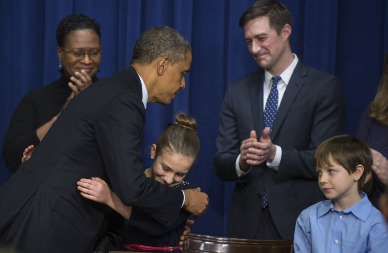 U.S. President Barack Obama hugs Julie Stokes as another school child Grant Fritz looks on after Obama signed executive orders to control gun violence in the South Court Auditorium on January 16, 2013 in Washington, DC. The economic cost -- in excess healthcare utilization, non-response to treatment, incarceration, loss of employment, decrease in productivity, and disability -- weighs heavily on families burdened with adversity but ultimately is borne by society as a whole, the study said. . UPI/Pat Benic