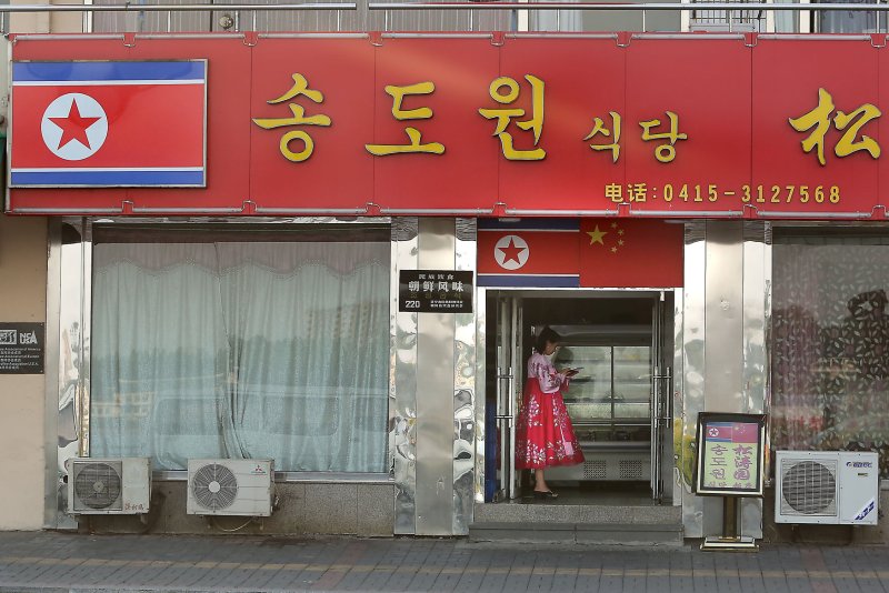 A North Korean woman and hostess stands outside a North Korean restaurant waiting for customers in Dandong, China's largest border city with North Korea. A North Korean diplomat is seeking the return of a dozen North Korean waitresses who were resettled in the South in 2016. Photo by Stephen Shaver/UPI