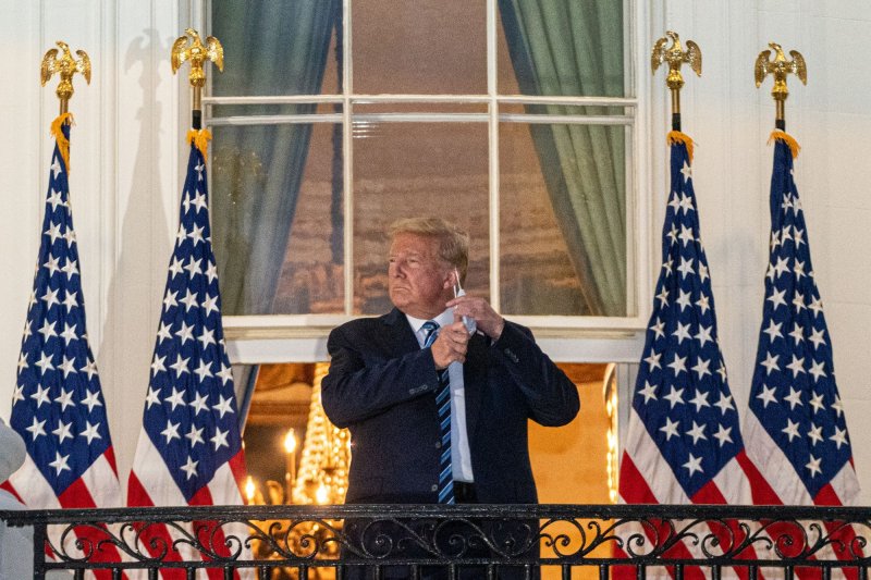President Donald Trump, who has COVID-19, takes off his mask Monday as he returns to the White House from Walter Reed National Military Medical Center. Photo by Ken Cedeno/UPI