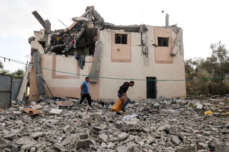 Palestinian men salvage belongings outside a building hit by an Israeli air strike in Khan Yunis in the southern Gaza Strip on Saturday. Rocket fire on Sunday briefly interrupted a cease-fire between the two sides. Photo by Ismael Mohamad/UPI