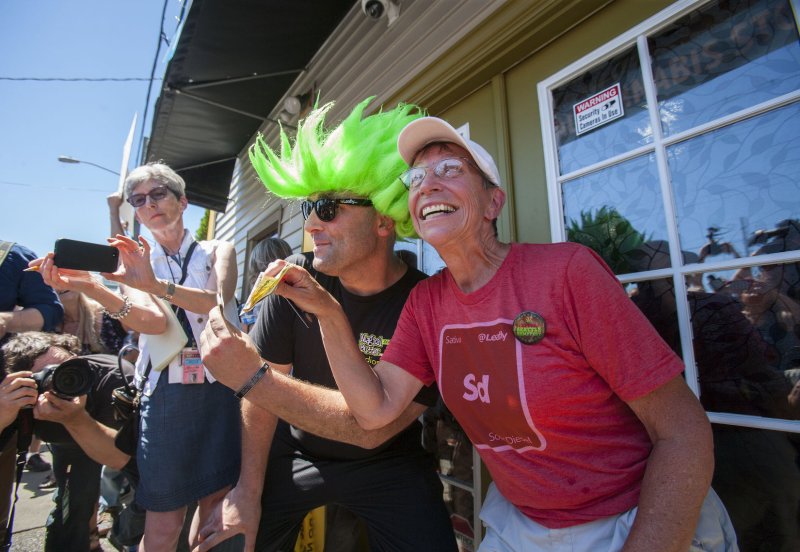 Retiree Deborah Greene, 65, and Jeremy Cooper, shows the media the money they will use to purchase marijuana in Cannabis City, WashingtonÕs first recreational marijuana store to open July, 8, 2014 in Seattle. Greene, a grandparent, was the first in line since 3 PM yesterday to purchase legal marijuana. Owner James Lathrop expects to sell all 10 pounds of pot at $15 to $20 per gram. Lathrop and his business manager had been working as many as 16 hours a day to prepare the business for its first customers. He said Cannabis City passed its two-hour state inspection last week. UPI/Jim Bryant