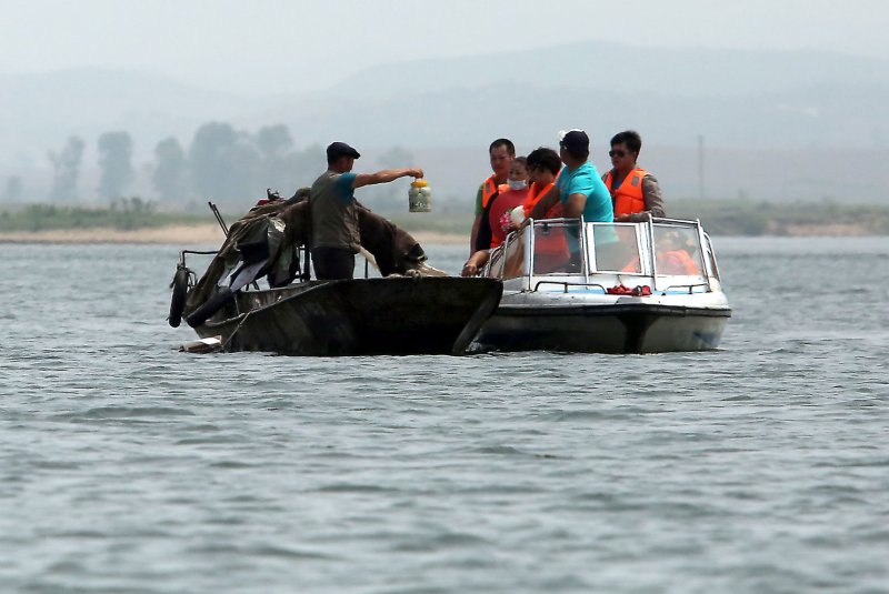 A North Korean man sells contraband pickled eggs, cigarettes, alcohol and ginseng to Korean, Japanese and Chinese tourists on the Yalu River, north of Dandong, China's largest border city with North Korea. There are now more than 380 “gray” marketplaces in North Korea. Photo by Stephen Shaver/UPI