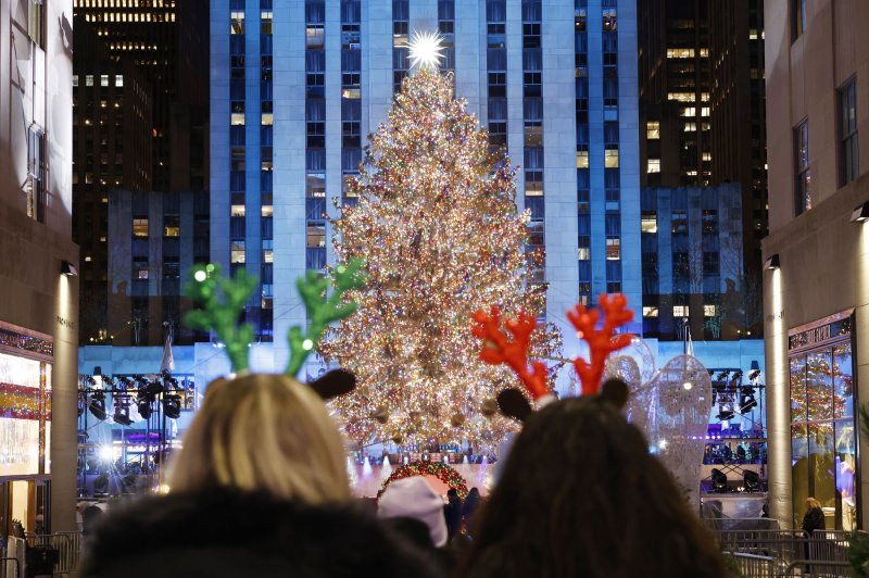 Two people wearing reindeer antlers stop to take photos of the Christmas tree lights after they are turned on for the first time at the 90th annual Rockefeller Center Christmas Tree Lighting Ceremony in New York City on Wednesday. The first official day of wintrer is Dec. 21. Photo by John Angelillo/UPI