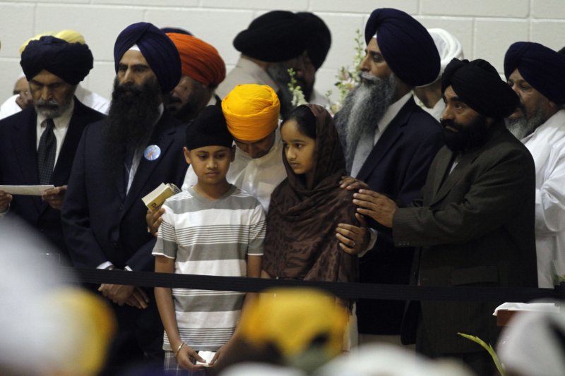 Mourners comforting the 11-year-old son and 12-year-old daughter of Prakash Singh, a victim of the Sikh temple mass murder, during a memorial service and visitation on August 10, 2012, at Oak Creek High School in Oak Creek, Wisconsin. The lone gunman, Wade Michael Page, a member of a racist neo-nazi group, killed six people, including himself, during Sunday services at the Sikh Temple on August 5. (File Photo by Allen Fredrickson/UPI)