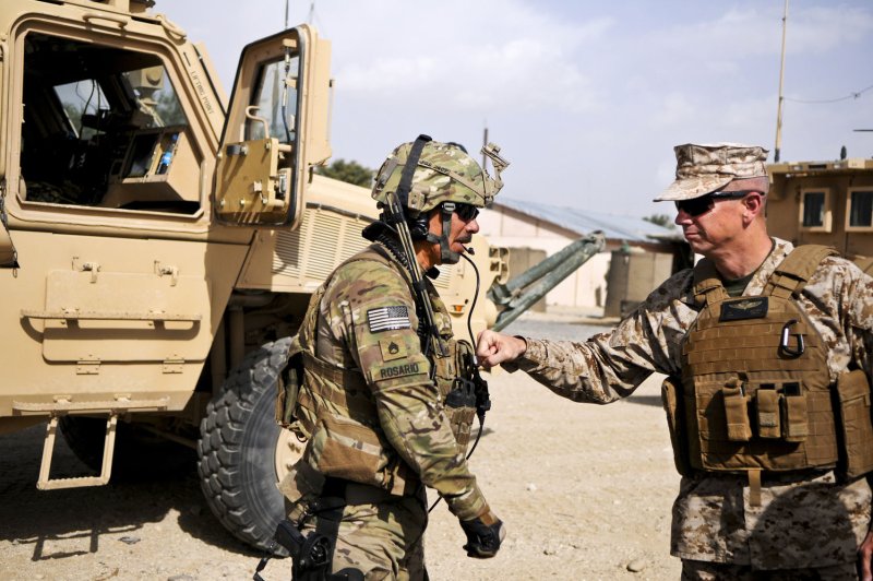 Marine Corps Gen. John R. Allen, commander of NATO and International Security Assistance Force troops in Afghanistan, gives a soldier assigned to Forward Operating Base Ghazni a thump on his body armor as he thanked him for his service and sacrifice on August 15, 2011. (UPI/Michael O'Conner/USAF)