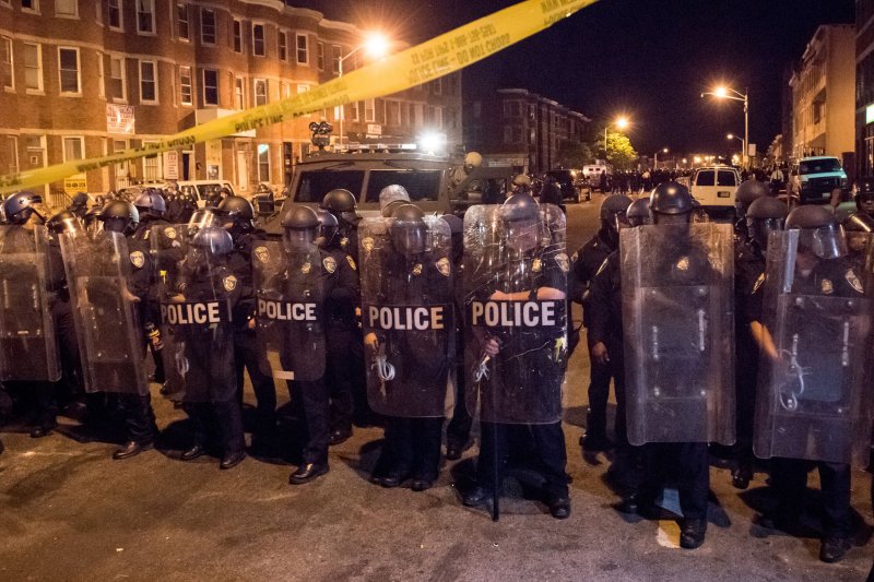 Police in riot gear line up with military rescue vehicle April 28 while local citizens pushed the limit of the 10 p.m. curfew in Baltimore. Six Baltimore police officers pleaded not guilty to charges related to the death of Freddie Gray. File photo by Ken Cedeno/UPI