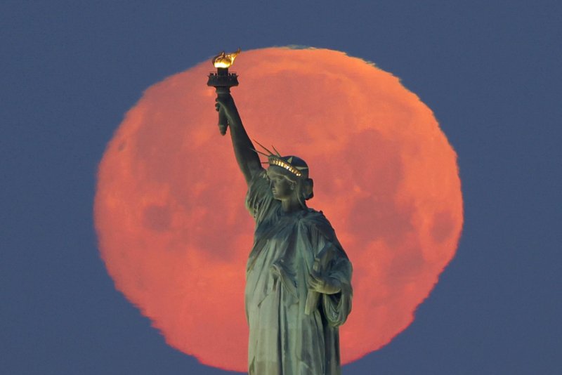 A Pink Supermoon sets behind the Statue of Liberty in New York City on April 26. File Photo by John Angelillo/UPI