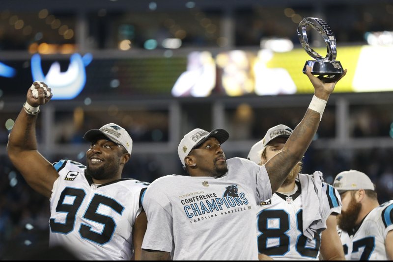 Carolina Panthers linebacker Thomas Davis lifts the NFC championship trophy as he and defensive end Charles Johnson, left, celebrate after the Panthers defeat the Arizona Cardinals 49-15 at Bank of America Stadium in Charlotte, North Carolina on January 24, 2016. Photo by Brian Westerholt/UPI