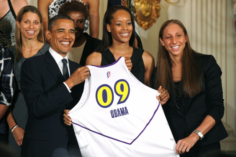 U.S. President Barack Obama receives a jersey from Pheniox Mercury's Tangela Smith (C) and Diana Taurasi. UPI/Kevin Dietsch