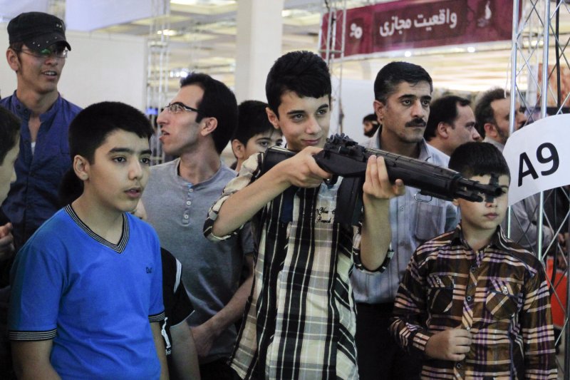 An Iranian boy plays with an assault rifle controller for a video game during the second International Computer Game Exhibition in Tehran, Iran on June 27, 2012. UPI/Maryam Rahmanian