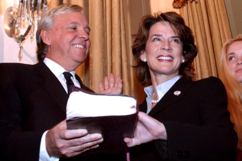 Anders Ebbesen holds a bible as his wife, Katherine Harris, R-Fla., is sworn in to the U.S. House of Representatives in 2003. (UPI/Michael Kleinfeld)