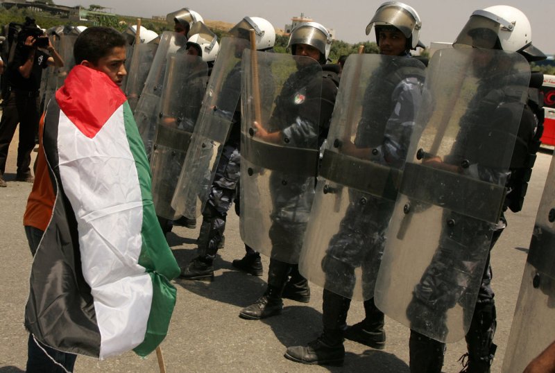 A boy wraps himself in a Palestinian flag as he stands in front of Hamas riot policemen during a protest near the Erez border crossing between Israel and northern Gaza Strip June 5, 2011, marking the 44th anniversary of the start of a 1967 Middle East War in which Israel captured East Jerusalem, the Gaza Strip, the West Bank and Golan Heights. UPI/Ismael Mohamad.