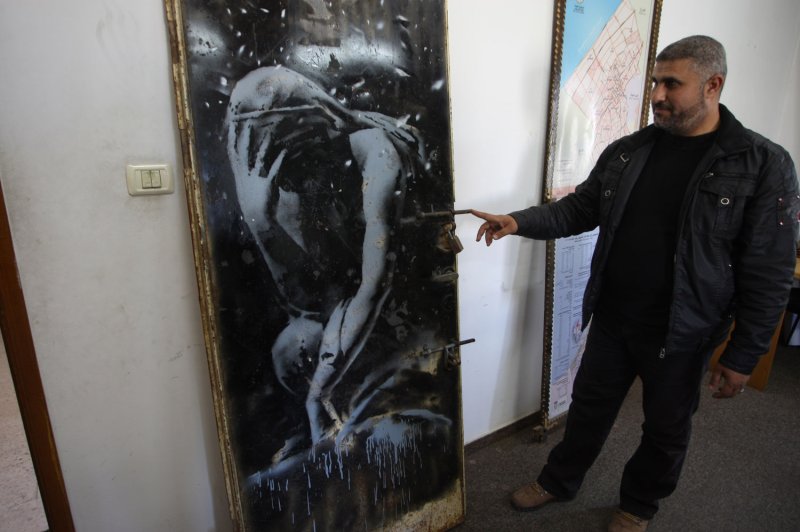A mural of a weeping woman, said to have been painted by British street artist Banksy, sits inside the library of Khan Younis local council in southern Gaza on April 14, 2015. The mural was painted on the door of a house that was destroyed during the 50-day war between Israel and Hamas militants in the summer of 2014. The art piece was bought for $175 by a Palestinian from a family who now feels tricked. Experts said it is a valuable art piece worth tens of thousands of dollars. The mural was seized by police in Gaza on April 10, 2015, the vendor and the purchaser said. Photo by Ismael Mohamad/UPI