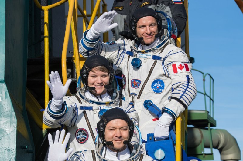Expedition 58 flight engineer David Saint-Jacques of the Canadian Space Agency, top, Flight Engineer Anne McClain of NASA, center, and Soyuz commander Oleg Kononenko of Roscosmos wave farewell prior to boarding the Soyuz MS-11 spacecraft for launch on December 3, 2018, in Baikonur, Kazakhstan. Photo by Aubrey Gemignani/NASA