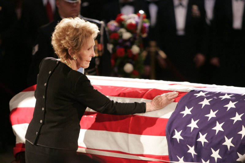 Former first lady Nancy Reagan touches the casket of her husband, former President Ronald Reagan, in the Capitol Rotunda on June 9, 2004. He died June 5 at age 93. File Photo by Peter Jones/UPI