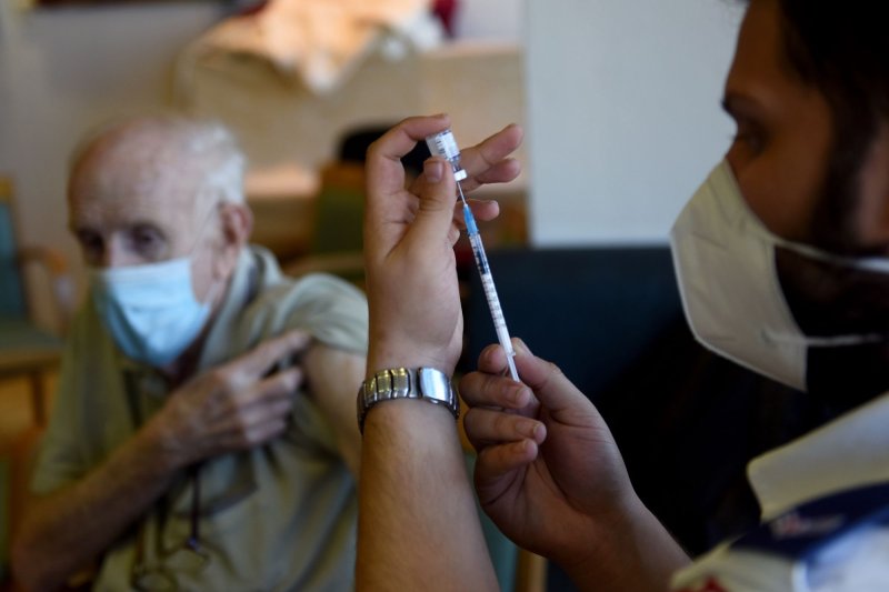 An elderly Israeli man waits to be is injected with the fourth COVID-19 Pfizer BioNTech vaccine by a Magen David Adam National Emergency Services worker in the Migdal Nofim Assisted Liiving Facility in Jerusalem, on January 6, 2022. File Photo by Debbie Hill/UPI