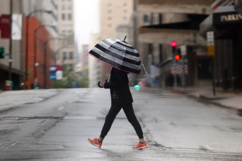 A woman with an umbrella crosses the normally busy Pine Street in downtown St. Louis on Saturday, April 25, 2020. The Stay at Home order plus a steady, cold rain has kept the streets empty. St. Louis has 2333 confirmed cases of the Coronavirus disease with 91 deaths. Photo by Bill Greenblatt/UPI | <a href="/News_Photos/lp/918aae68d1477720ea05905aa013970e/" target="_blank">License Photo</a>