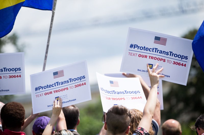 Demonstrators hold up signs in support of transgender troops outside Capitol Hill on July 26. Photo by Erin Schaff/UPI